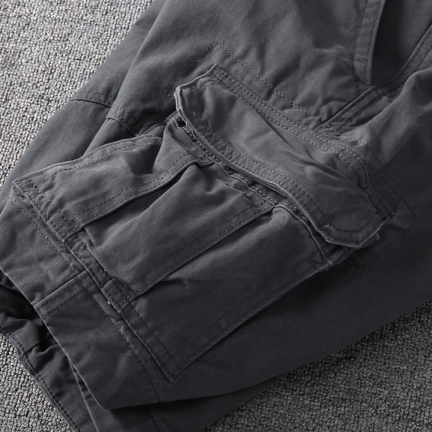 Side view of dark gray cargo shorts with layered pocket flaps and reinforced stitching