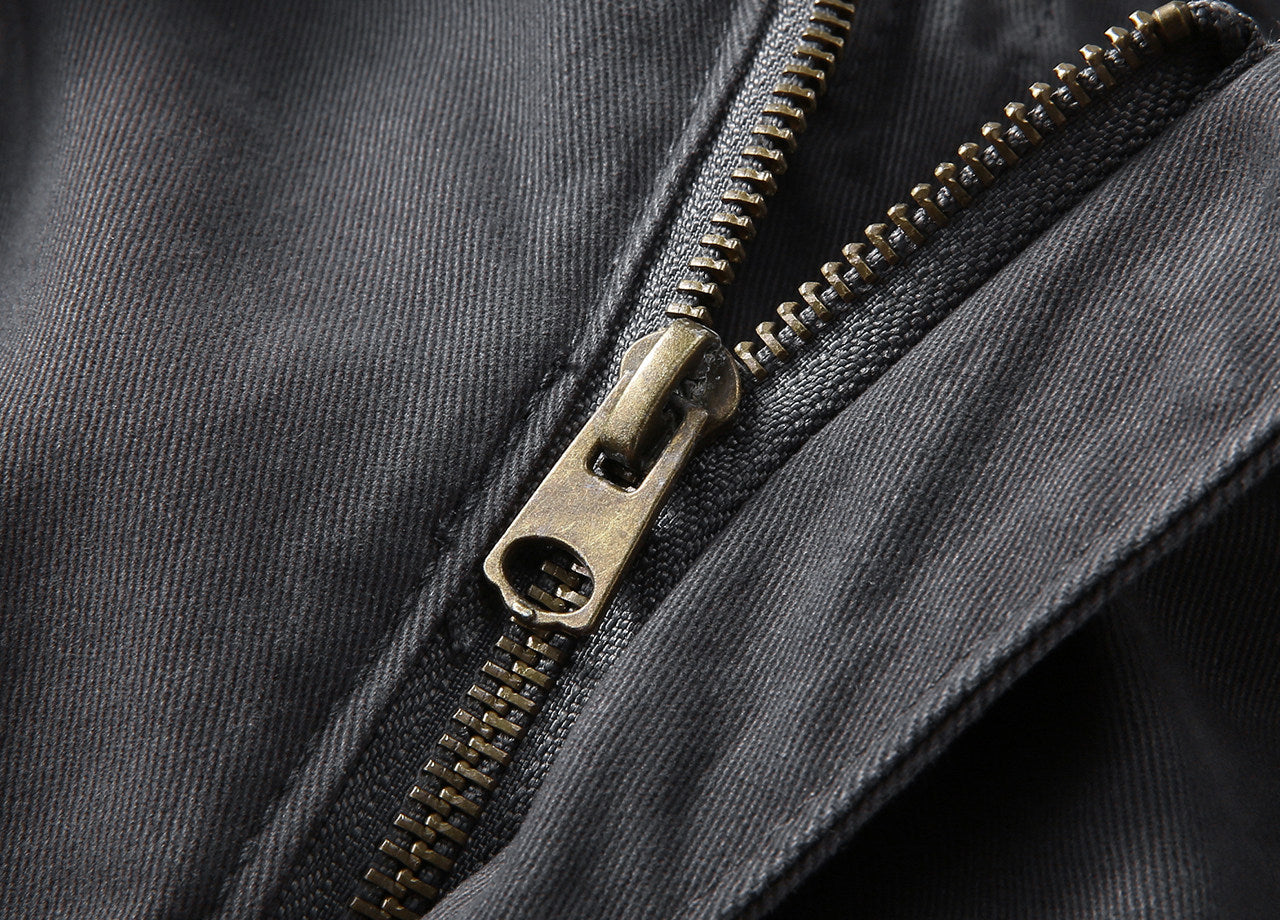 Close-up of zipper fly on gray cargo shorts with metal teeth and brass-toned hardware