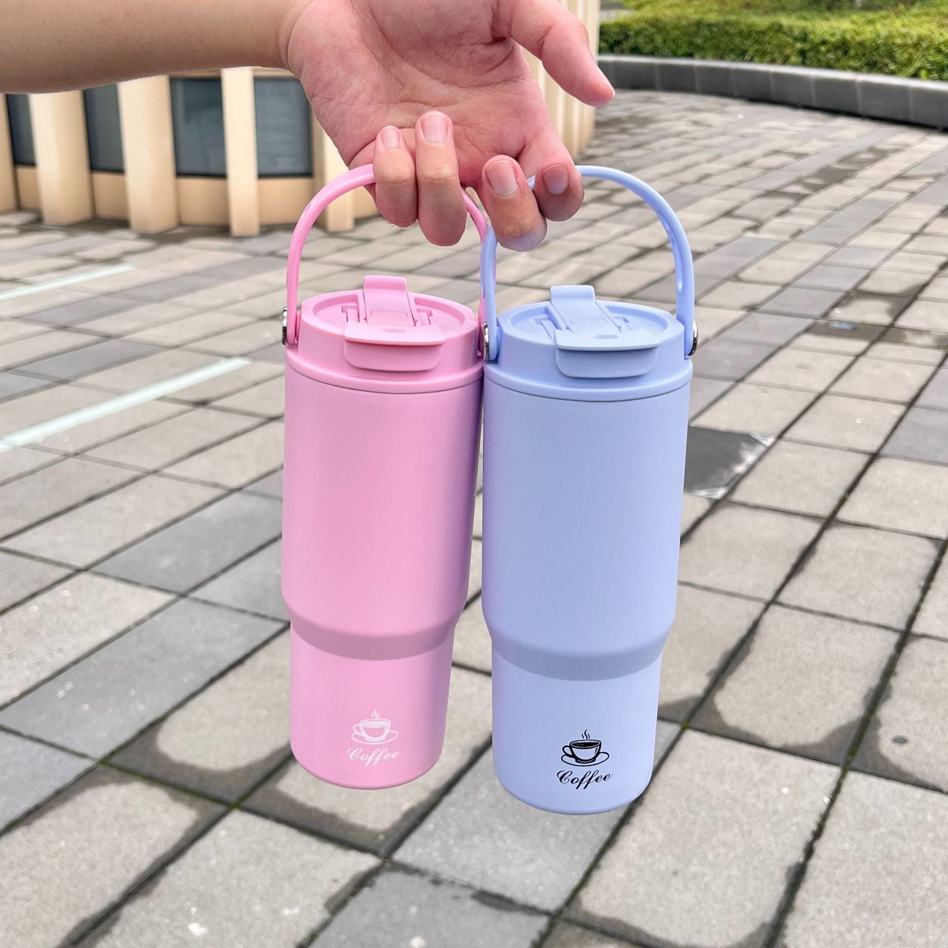 Portable insulated coffee bottles in pink and light blue with carry handles and lids