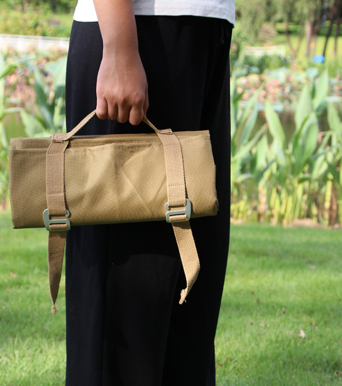 Khaki waterproof picnic and camping mat carry bag held by webbing handle straps.