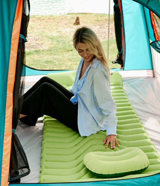 Emerald green inflatable camping sleeping pad with built-in pillow, positioned inside tent