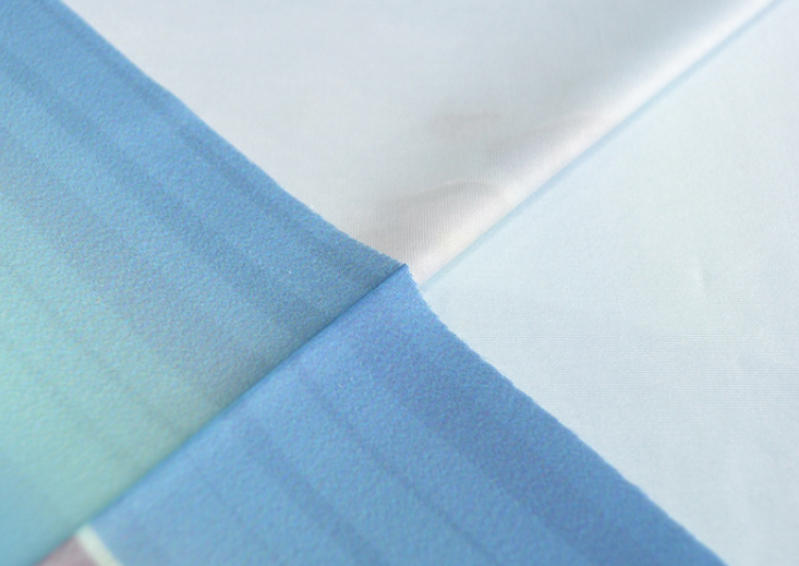 Light blue seamless stretch face mask fabric close-up with stitched seam