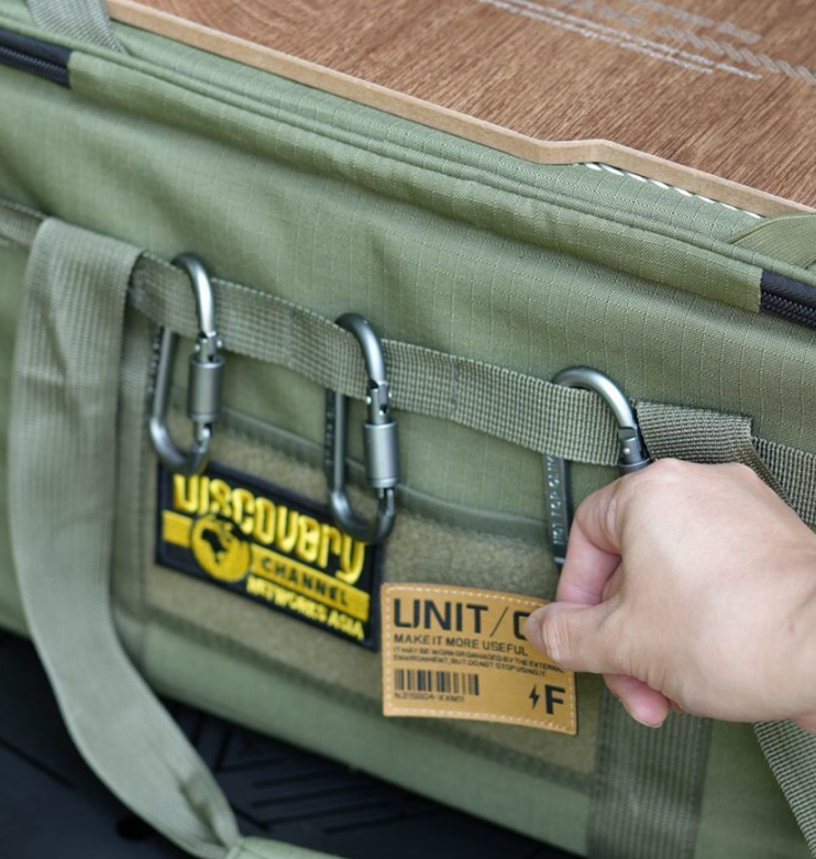 Green tactical storage bag front pocket with metal clips and woven label patch