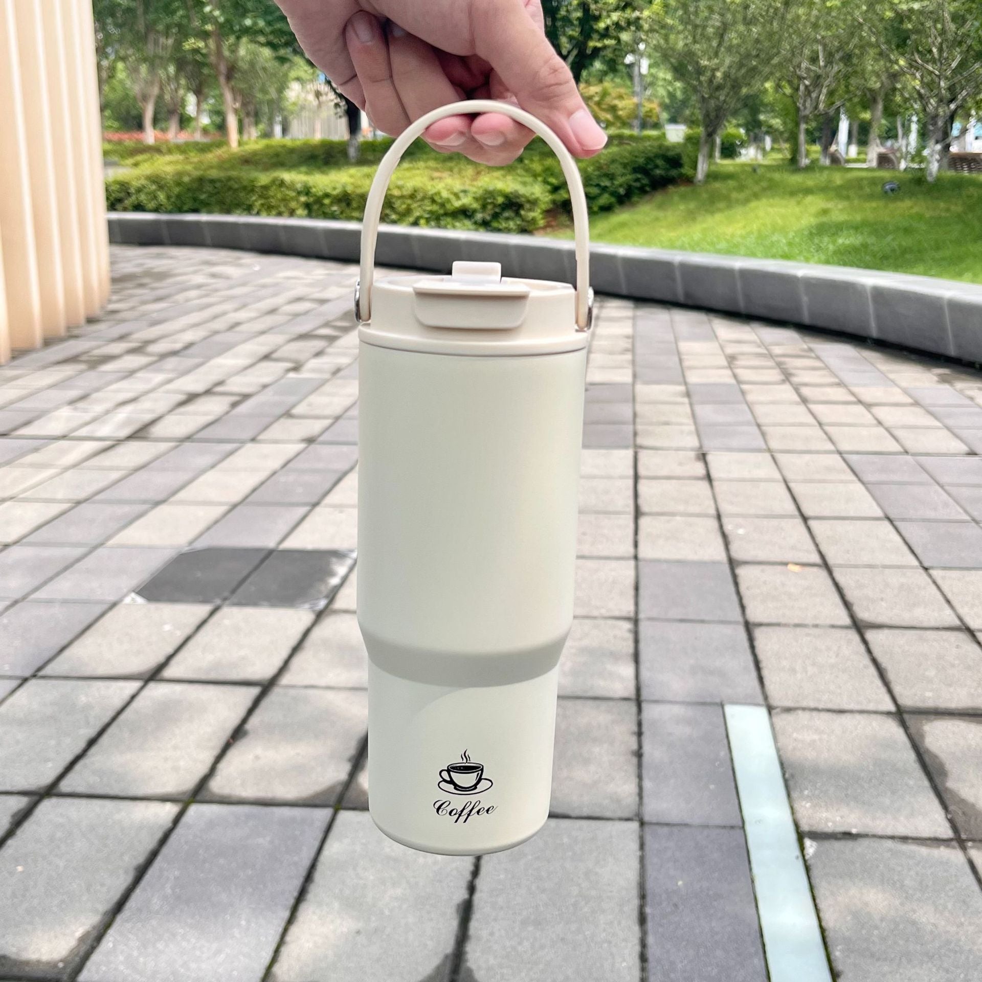 Portable stainless steel insulated bottle, white, held by handle